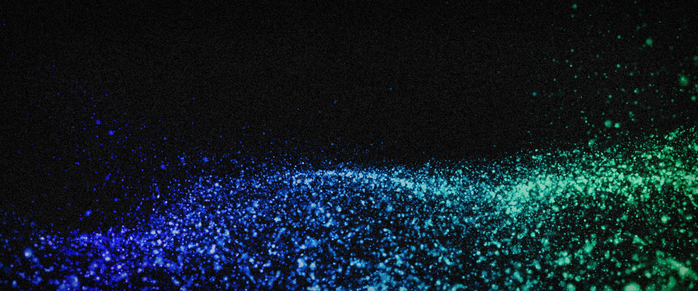 Abstract image showing a wave of particles or droplets in blue and green