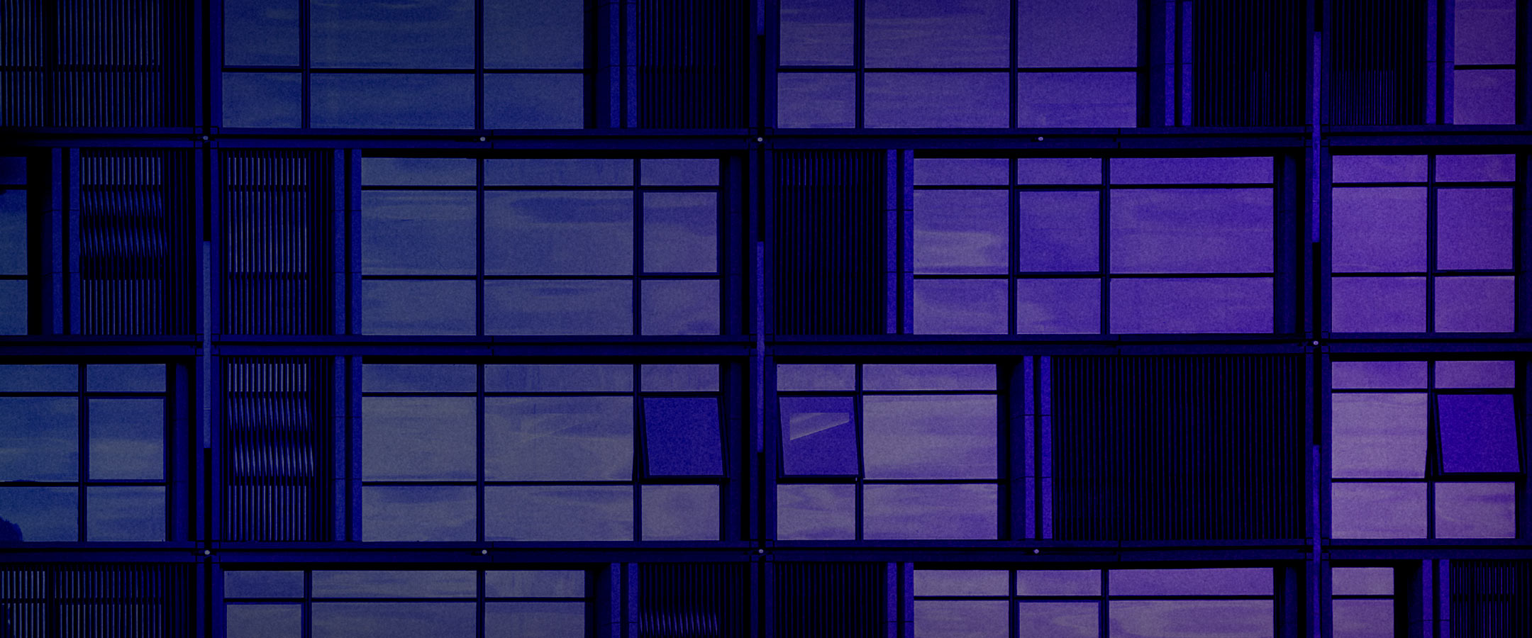 Abstract photo of exterior of a large building with large glass windows, colorized in blue and purple