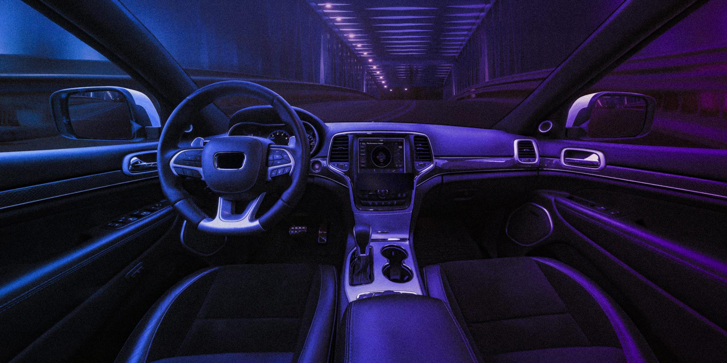 Photograph of the interior of a car, including steering wheel and dashboard, from the driver’s perspective