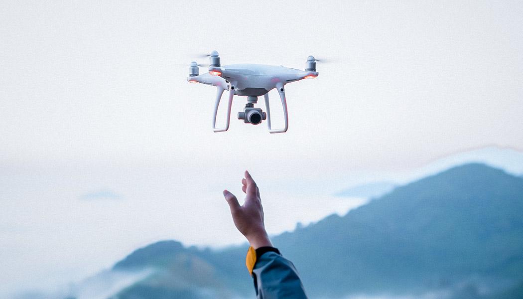 Silhouette of a quadcopter drone flying in front of a blurred background, overlaid with technical illustration of lines