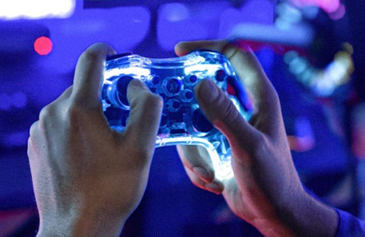 Brightly colored, close-up photograph of a pair of hands holding a gaming controller