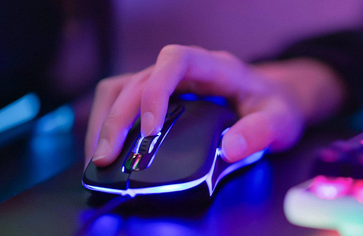 Brightly colored, close-up photograph of a hand on a gaming mouse