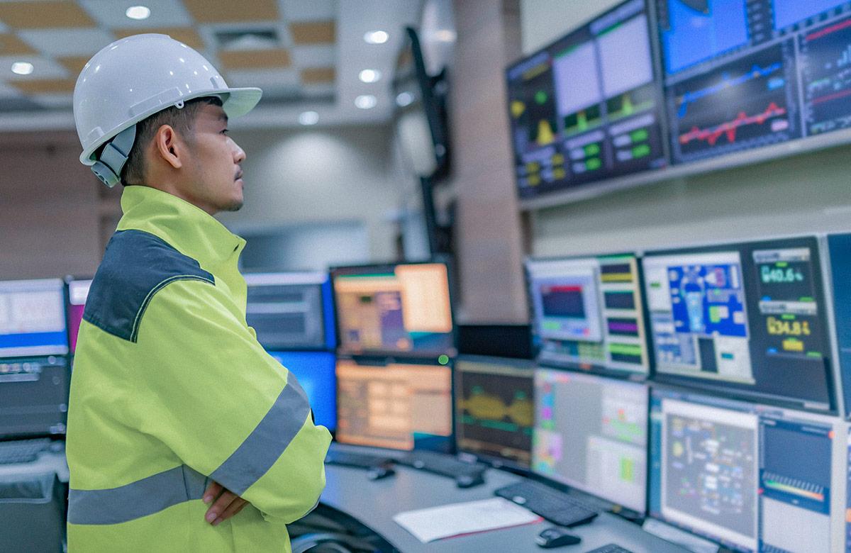 Photograph of a man observing a mechanical dashboard with many screens and control panels