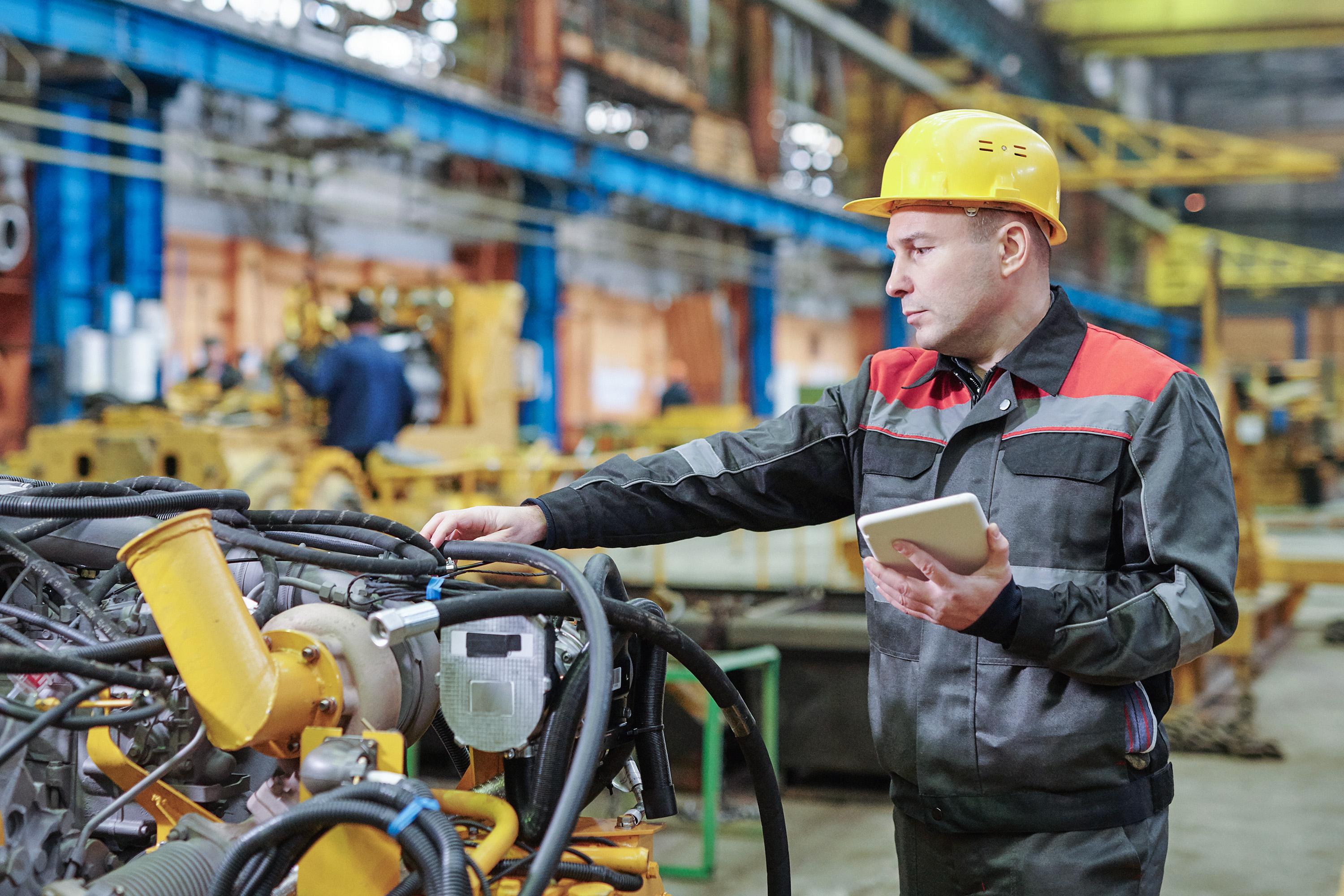 Photograph of man examining industrial equipment inside a factory