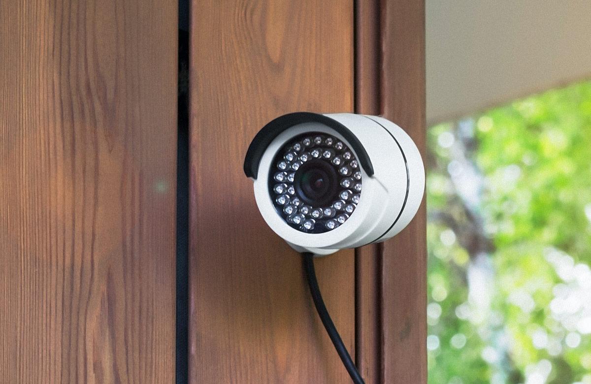 White security camera on the wall of a wooden house