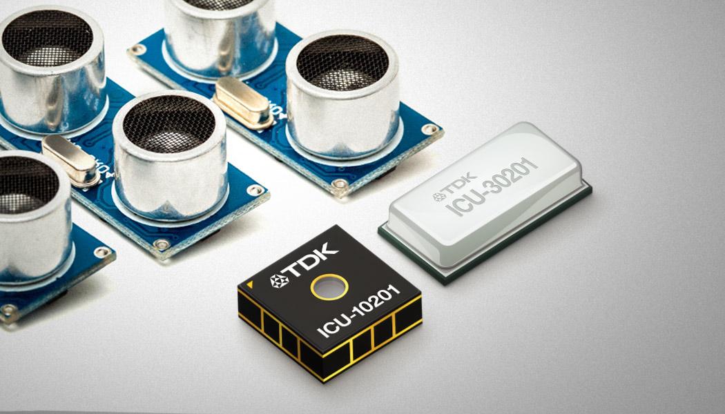 Two small TDK microchips next to a series of three classic ultrasonic sensors