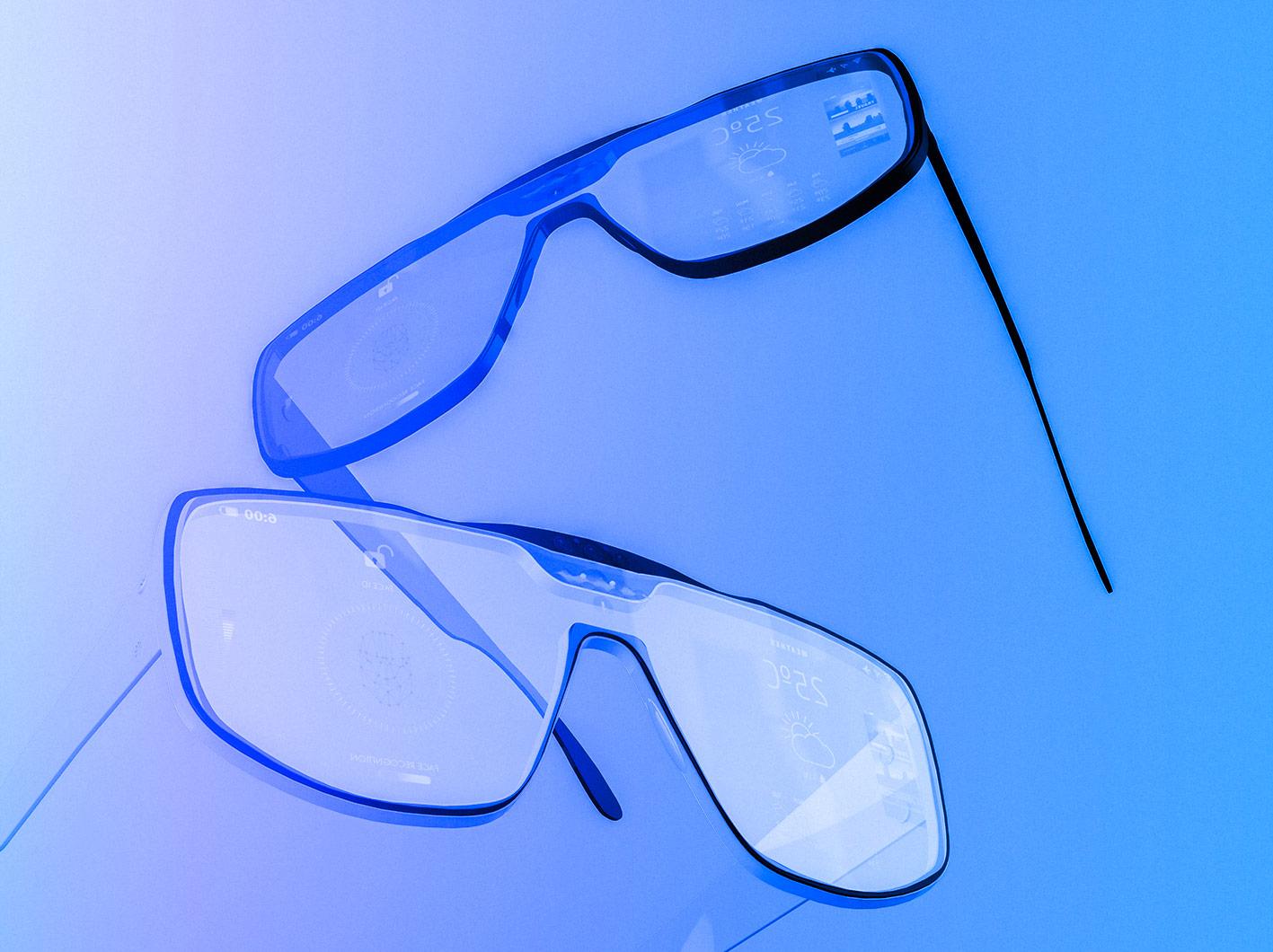 Photograph of two pairs of augmented reality smartglasses over a blue gradient background