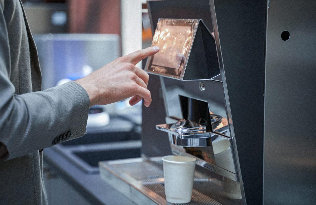 Photograph of person interacting with an automatic coffee machine