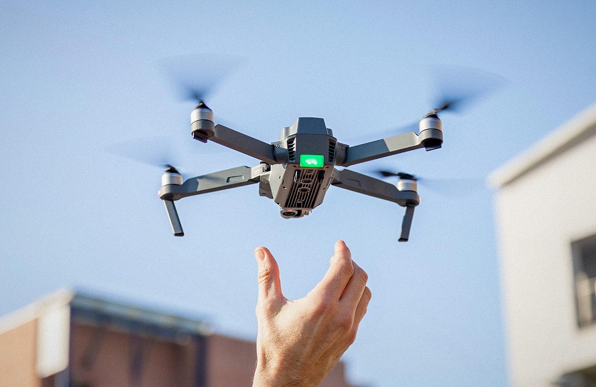 Photograph of a drone in flight, hovering near a person’s outstretched hand