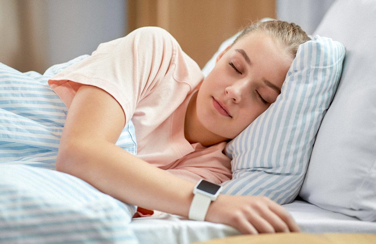 Girl with smart watch sleeping in bed at home
