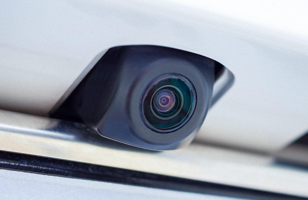 Extreme close-up on rear view camera lens and housing on a white vehicle