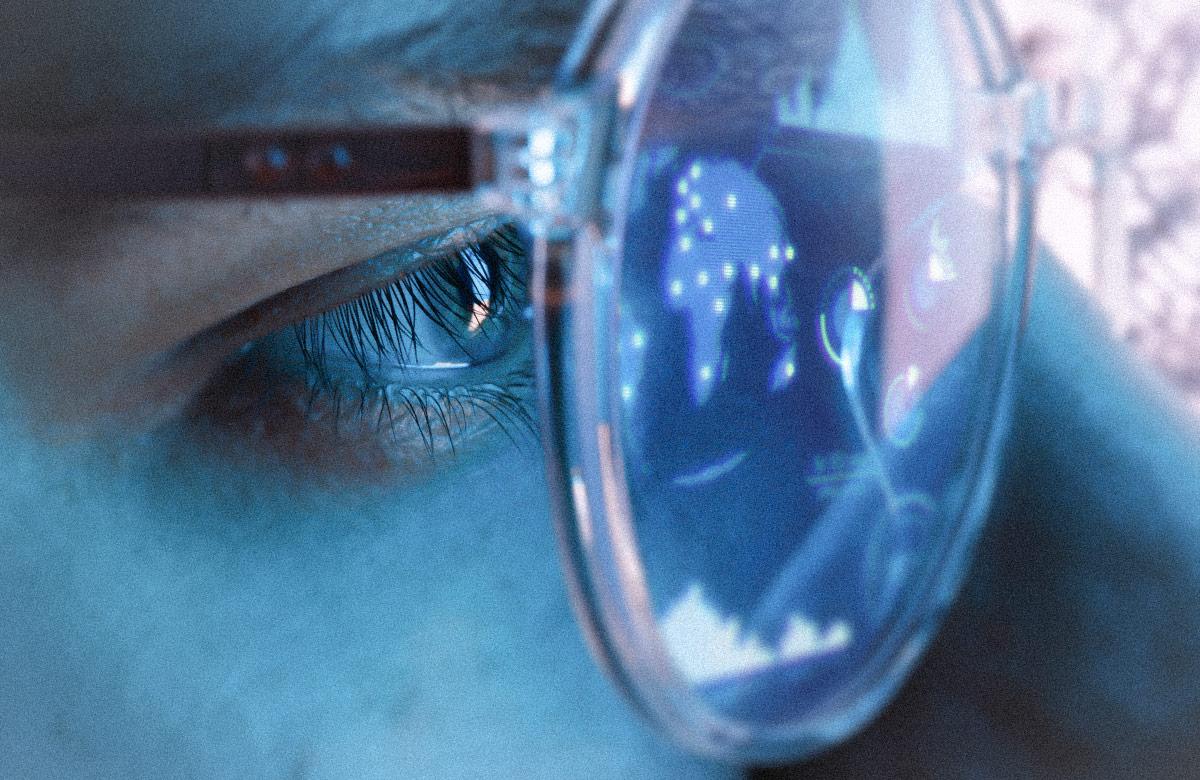 Close-up view of blue eye in glasses with futuristic holographic interface to display data