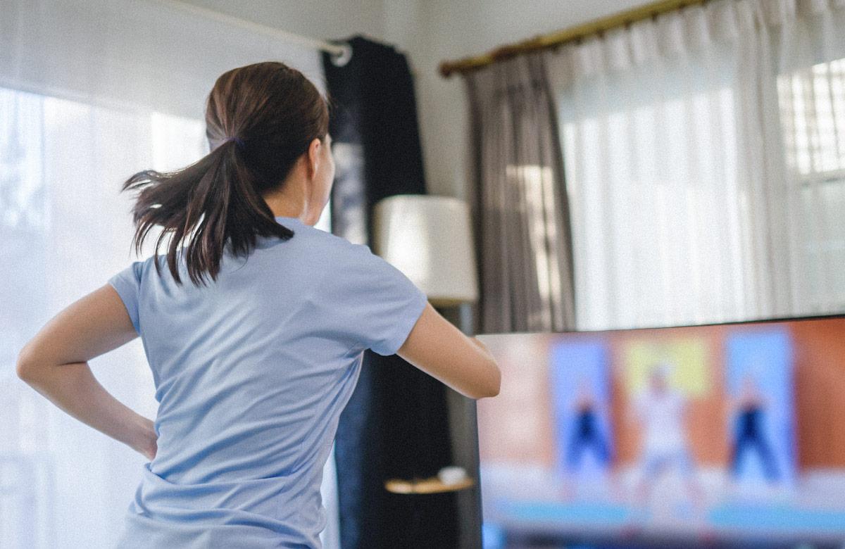 Brunette woman doing aerobic dance watching streaming exercise class.