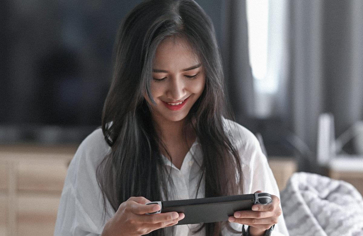 Young woman playing video games on tablet in living room.