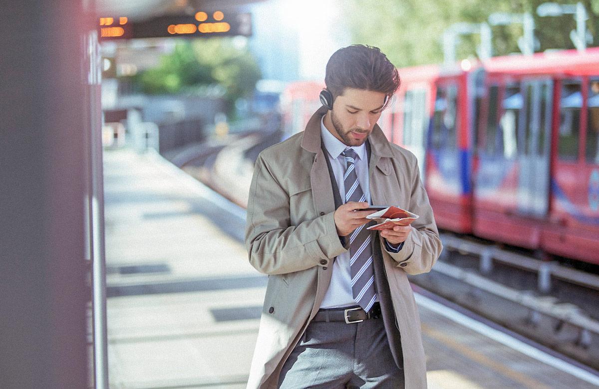 Man using smartphone while standing on a train platform
