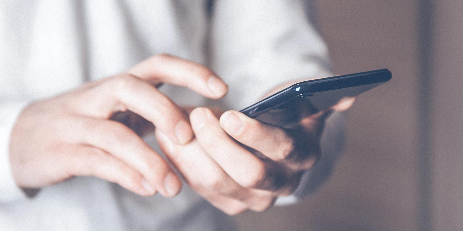 Close-up of young man holding black smartphone in hand