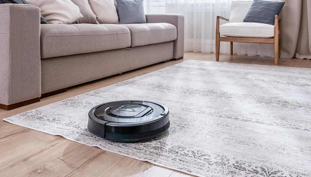 Robotic vacuum cleaner navigating off area rug onto hardwood floor