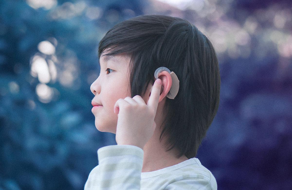 Boy with hearing aid on nature background
