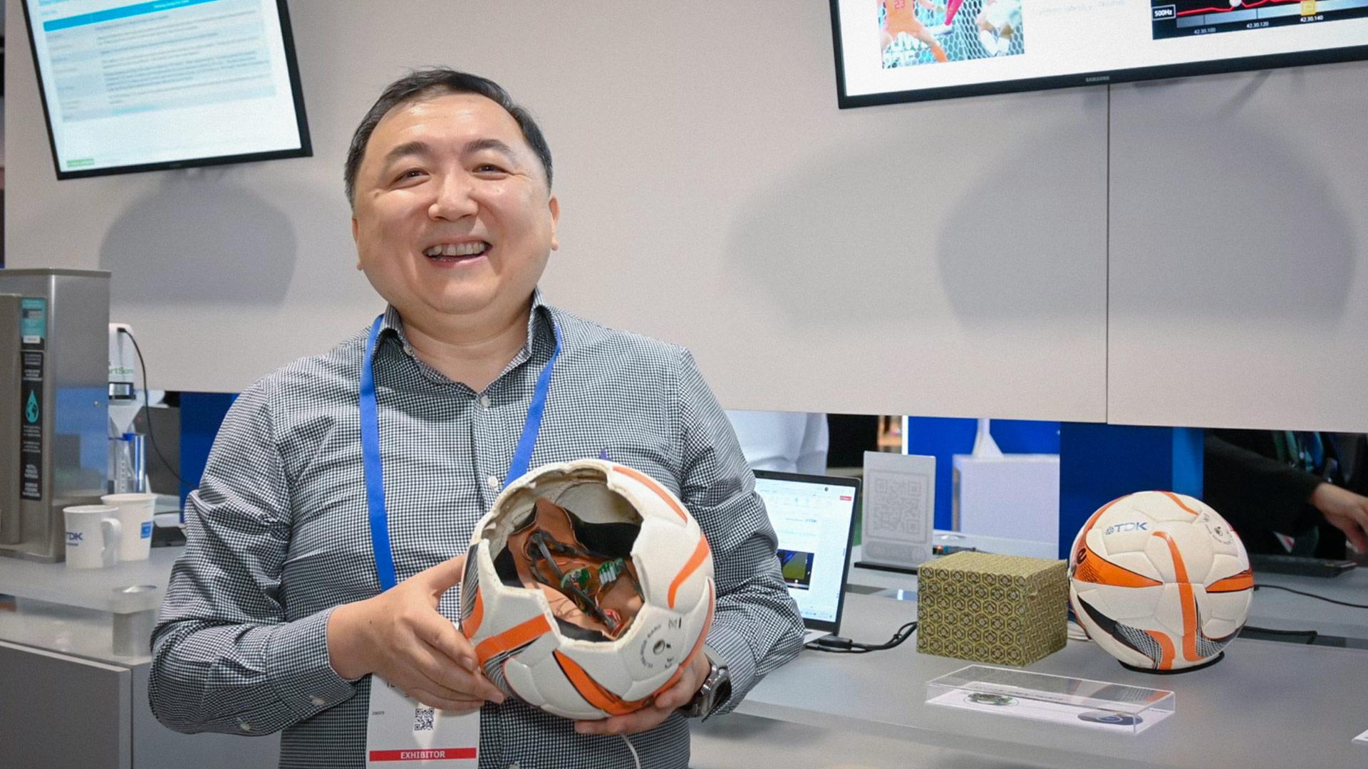 Man holding a soccer ball that has been cut open to reveal technological hardware